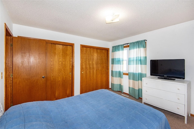 carpeted bedroom featuring two closets and a textured ceiling