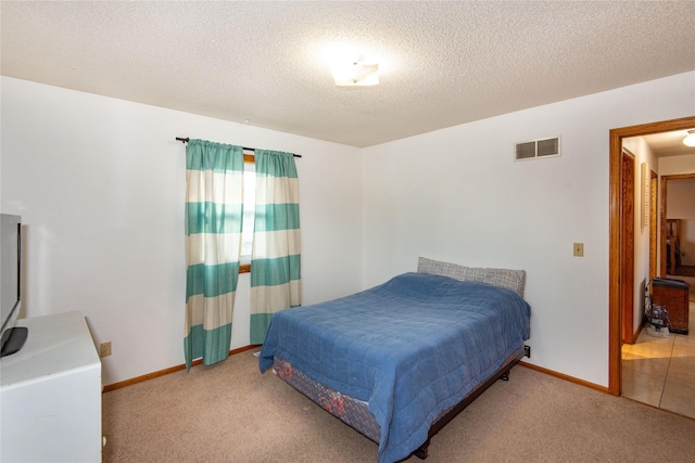 bedroom featuring light carpet and a textured ceiling