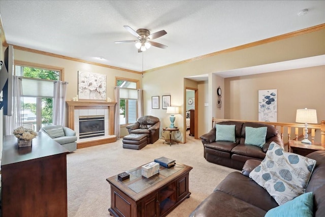 living room featuring a textured ceiling, a fireplace, ornamental molding, ceiling fan, and light colored carpet