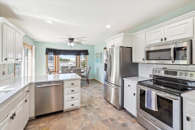 kitchen with ceiling fan, kitchen peninsula, white cabinets, and stainless steel appliances