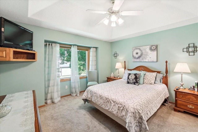 carpeted bedroom with ceiling fan and a tray ceiling