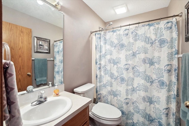 bathroom with toilet, vanity, walk in shower, and a textured ceiling