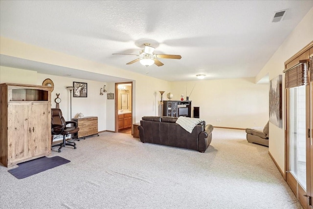 carpeted living room featuring ceiling fan and a textured ceiling