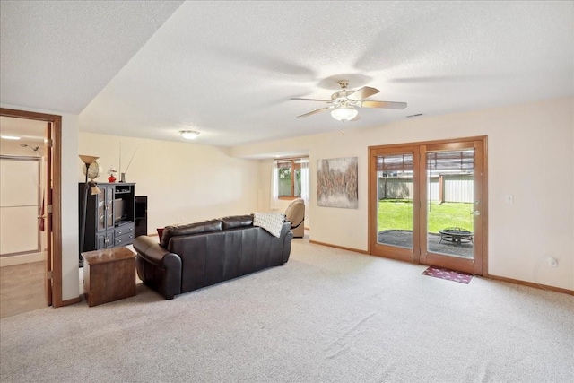 carpeted living room with a textured ceiling and ceiling fan