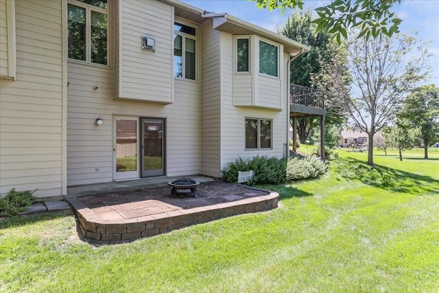 back of house with an outdoor fire pit, a yard, and a patio