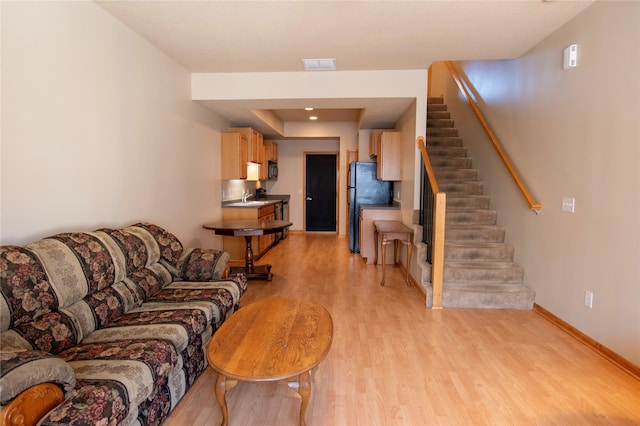 living room featuring sink and light hardwood / wood-style floors