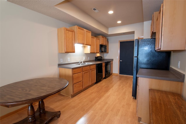 kitchen with light brown cabinetry, light hardwood / wood-style flooring, and black appliances