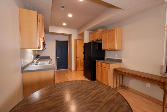 kitchen featuring black fridge, light brown cabinetry, light hardwood / wood-style flooring, and sink