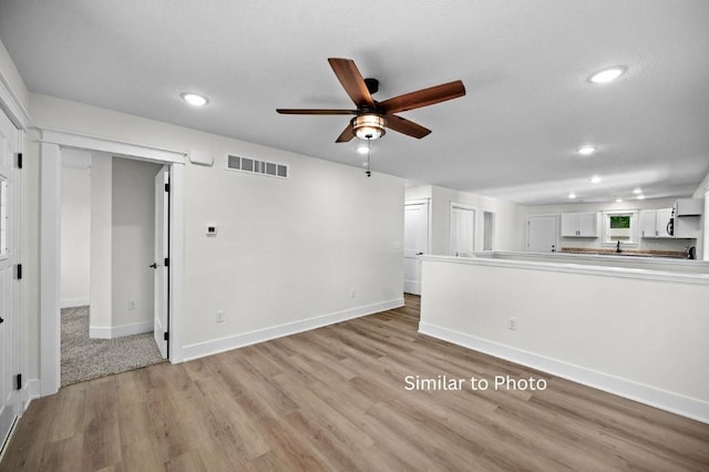 unfurnished living room featuring ceiling fan and light wood-type flooring