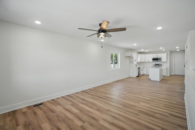 2527 Shaw St, Des Moines, IA 50317 - unfurnished living room with a ceiling fan, recessed lighting, light wood-type flooring, baseboards, and a sink