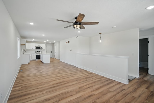 2527 Shaw St, Des Moines, IA 50317 - unfurnished living room featuring a ceiling fan, recessed lighting, light wood-style floors, baseboards, and a sink