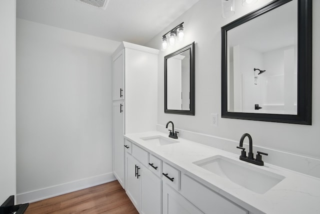 2527 Shaw St, Des Moines, IA 50317 - bathroom with double vanity, wood finished floors, and baseboards