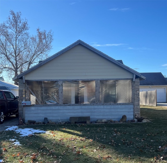 view of side of home featuring a sunroom and a lawn