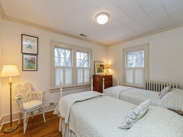 bedroom with multiple windows, hardwood / wood-style floors, radiator heating unit, and ornamental molding