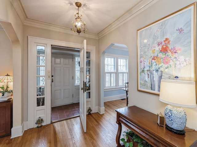 entrance foyer featuring crown molding, hardwood / wood-style floors, and a notable chandelier