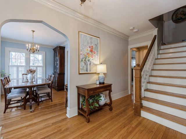 stairs featuring crown molding, a chandelier, and hardwood / wood-style flooring