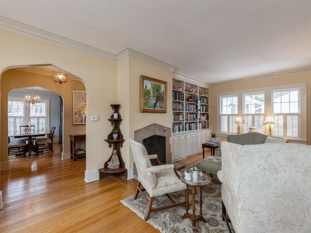 living area featuring built in shelves, a notable chandelier, a wealth of natural light, and light hardwood / wood-style flooring