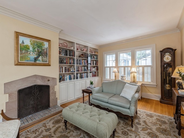 sitting room with crown molding, light hardwood / wood-style floors, a tile fireplace, and built in shelves