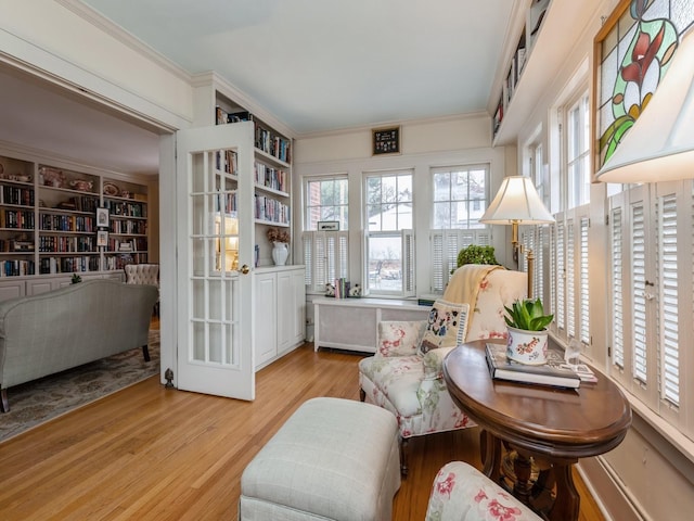 living area featuring ornamental molding, built in features, light hardwood / wood-style flooring, and radiator heating unit