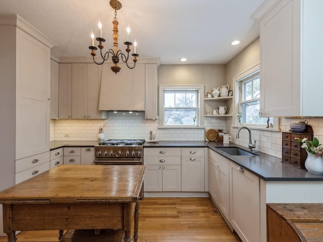 kitchen with white cabinetry, a notable chandelier, light wood-type flooring, hanging light fixtures, and sink