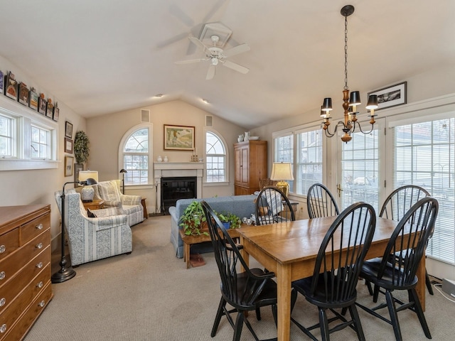 dining room featuring ceiling fan with notable chandelier, light colored carpet, and lofted ceiling