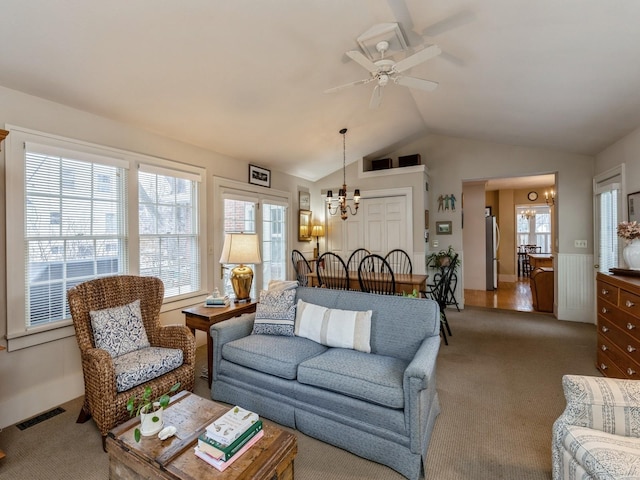 living room featuring ceiling fan with notable chandelier, plenty of natural light, carpet, and lofted ceiling