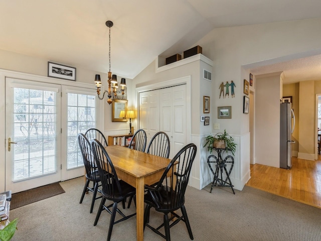 carpeted dining space featuring vaulted ceiling and a chandelier