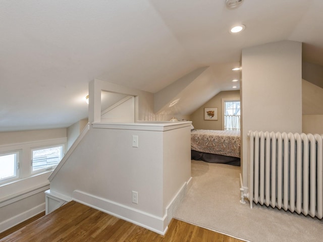 additional living space featuring radiator, vaulted ceiling, and light wood-type flooring