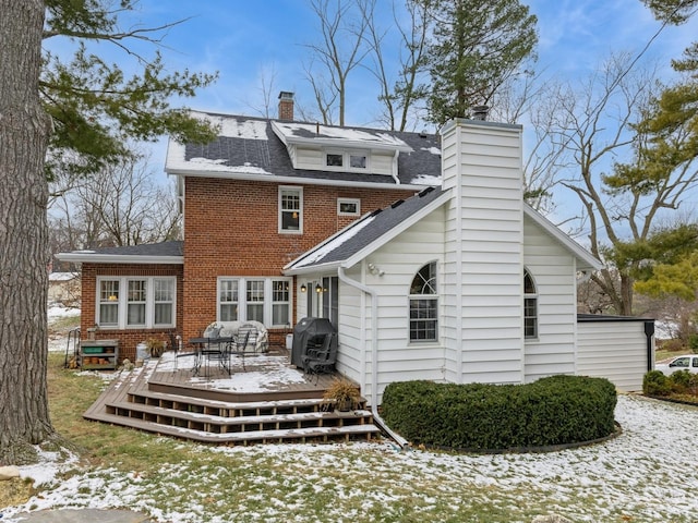 snow covered back of property with a deck