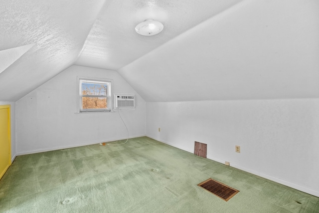 additional living space featuring a textured ceiling, carpet flooring, lofted ceiling, and a wall mounted AC