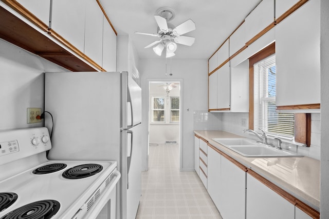 kitchen with ceiling fan, backsplash, white electric range, sink, and white cabinetry