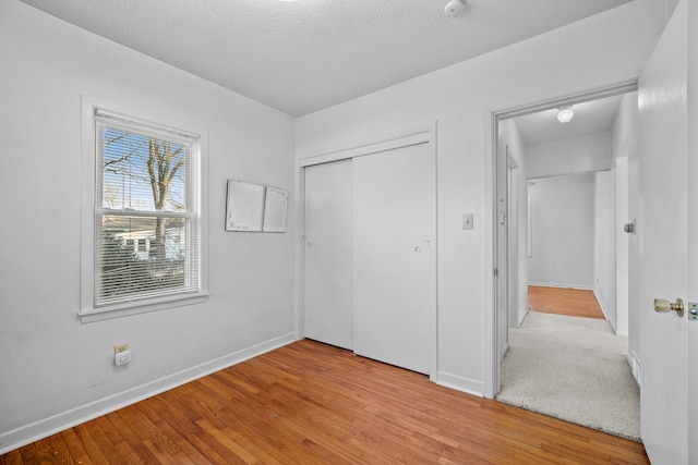 unfurnished bedroom featuring a closet, a textured ceiling, and light hardwood / wood-style floors