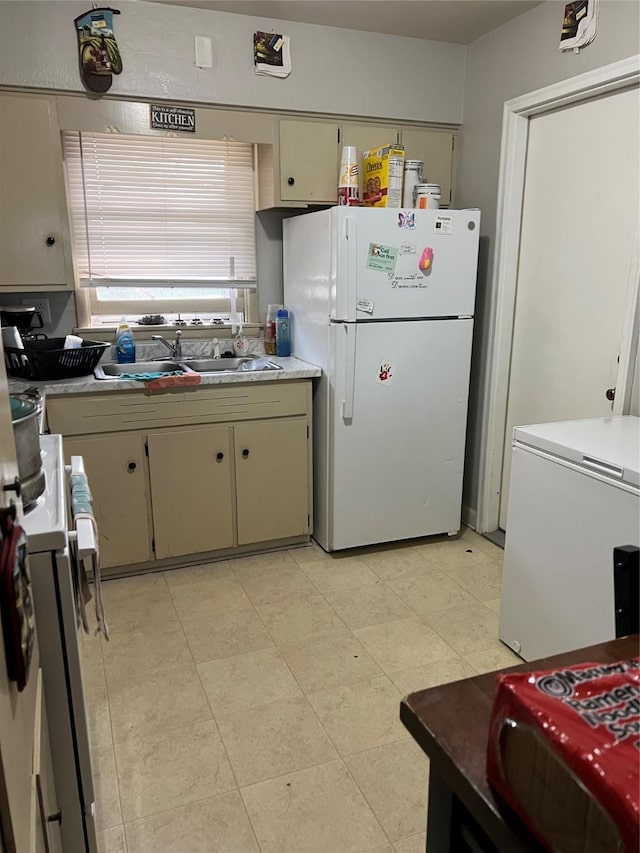 kitchen with sink, cream cabinetry, and white appliances