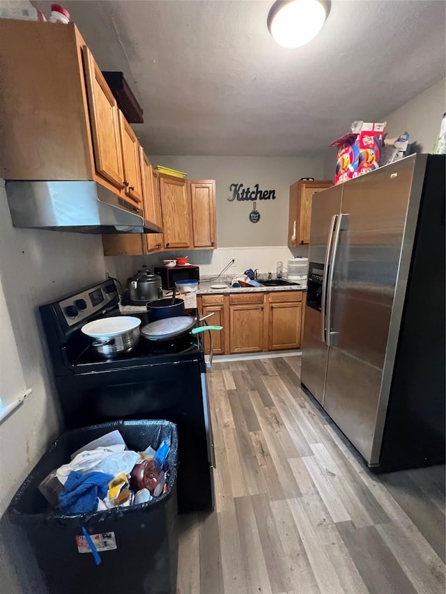 kitchen featuring sink, electric range, stainless steel fridge, and light wood-type flooring