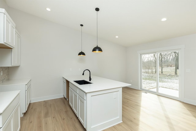 2390 Emma Ave, Des Moines, IA 50321 - kitchen featuring a peninsula, light wood finished floors, light countertops, pendant lighting, and white cabinetry