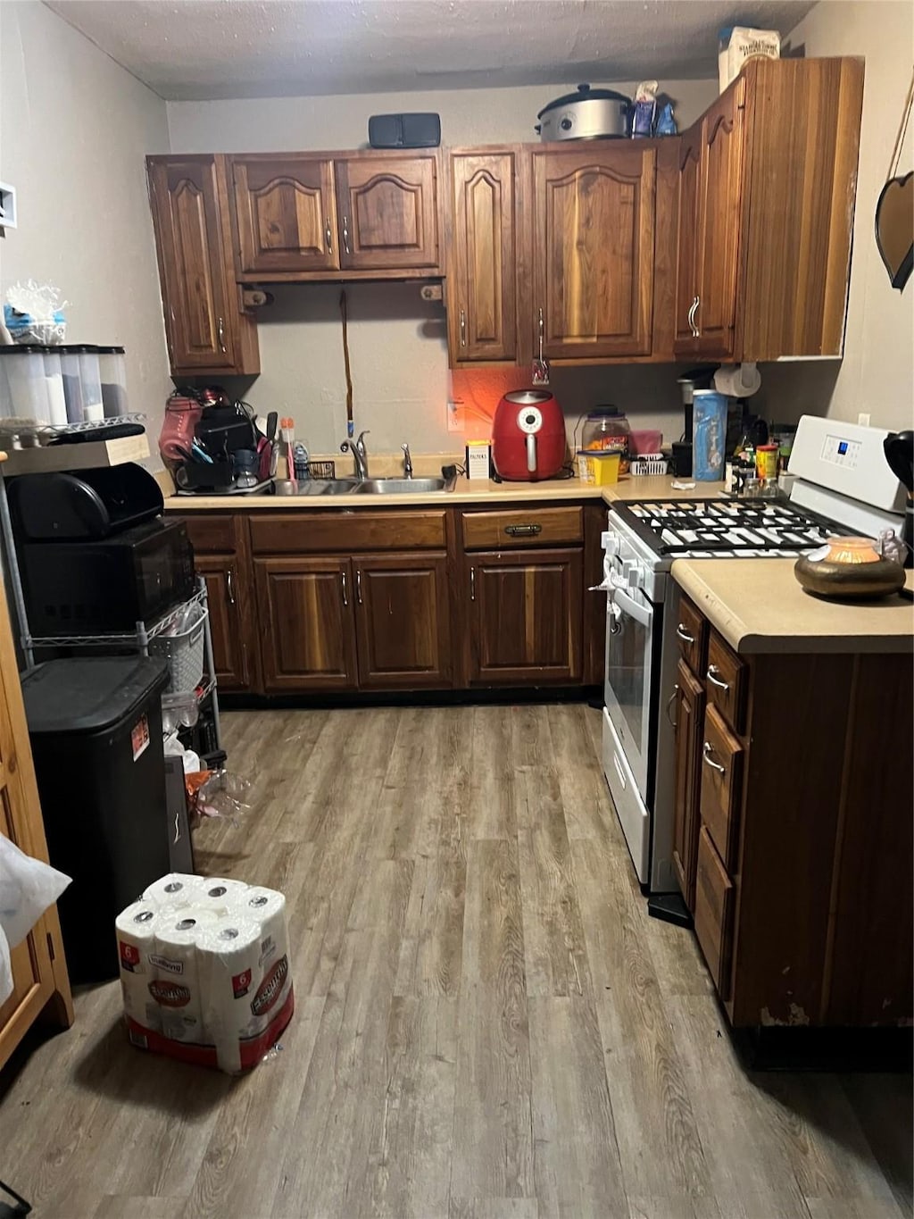 kitchen with light wood-type flooring, sink, white gas range, and dark brown cabinetry