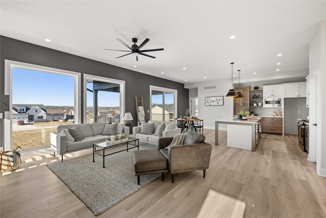 living room featuring ceiling fan and light hardwood / wood-style floors