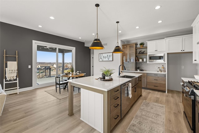 kitchen featuring white cabinetry, an island with sink, stainless steel appliances, pendant lighting, and sink