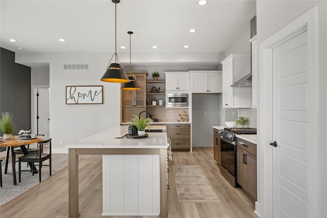 kitchen featuring white cabinetry, stainless steel appliances, backsplash, decorative light fixtures, and a center island