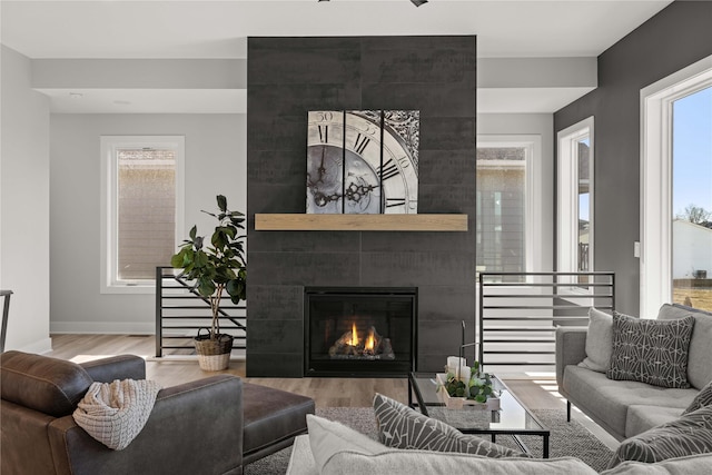 living room featuring wood-type flooring, plenty of natural light, and a tile fireplace