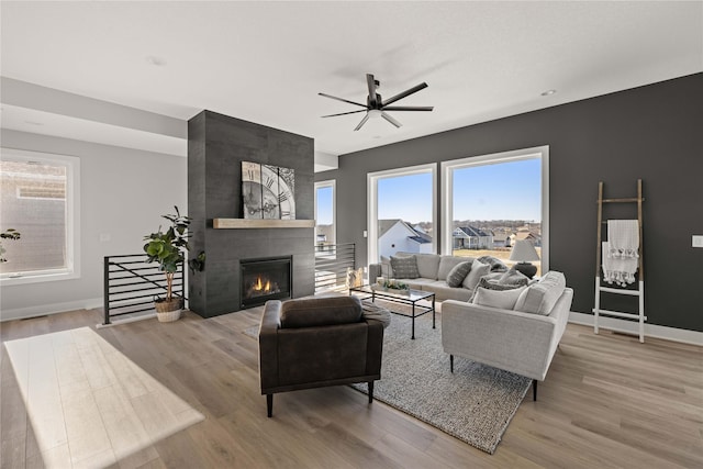 living room with ceiling fan, light hardwood / wood-style flooring, and a tiled fireplace