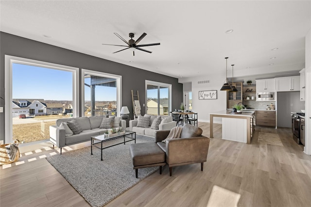 living room featuring ceiling fan, light hardwood / wood-style floors, and sink