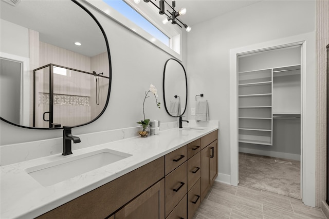 bathroom featuring a shower with shower door, vanity, and an inviting chandelier