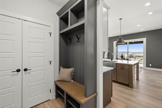 mudroom featuring sink, built in shelves, and light wood-type flooring