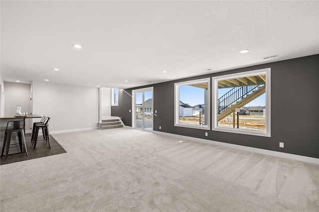 interior space featuring a textured ceiling, bar, and dark colored carpet