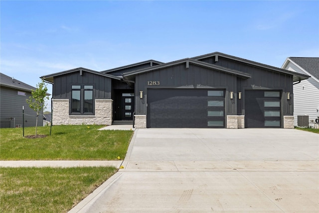 contemporary house featuring board and batten siding, stone siding, an attached garage, and concrete driveway