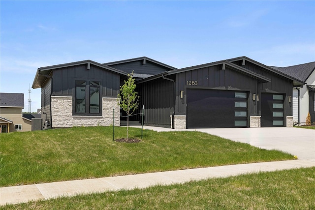 view of front of property with board and batten siding, stone siding, a garage, a front lawn, and driveway