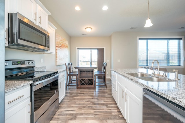 kitchen featuring pendant lighting, white cabinetry, stainless steel appliances, a healthy amount of sunlight, and sink