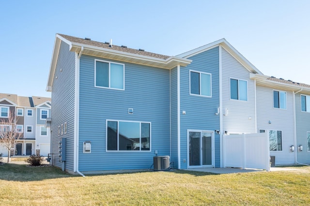 rear view of property with central AC unit and a yard