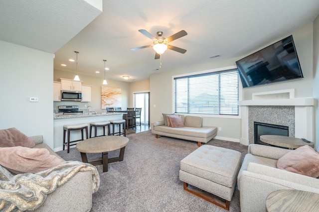 living room with ceiling fan, sink, carpet floors, and a textured ceiling